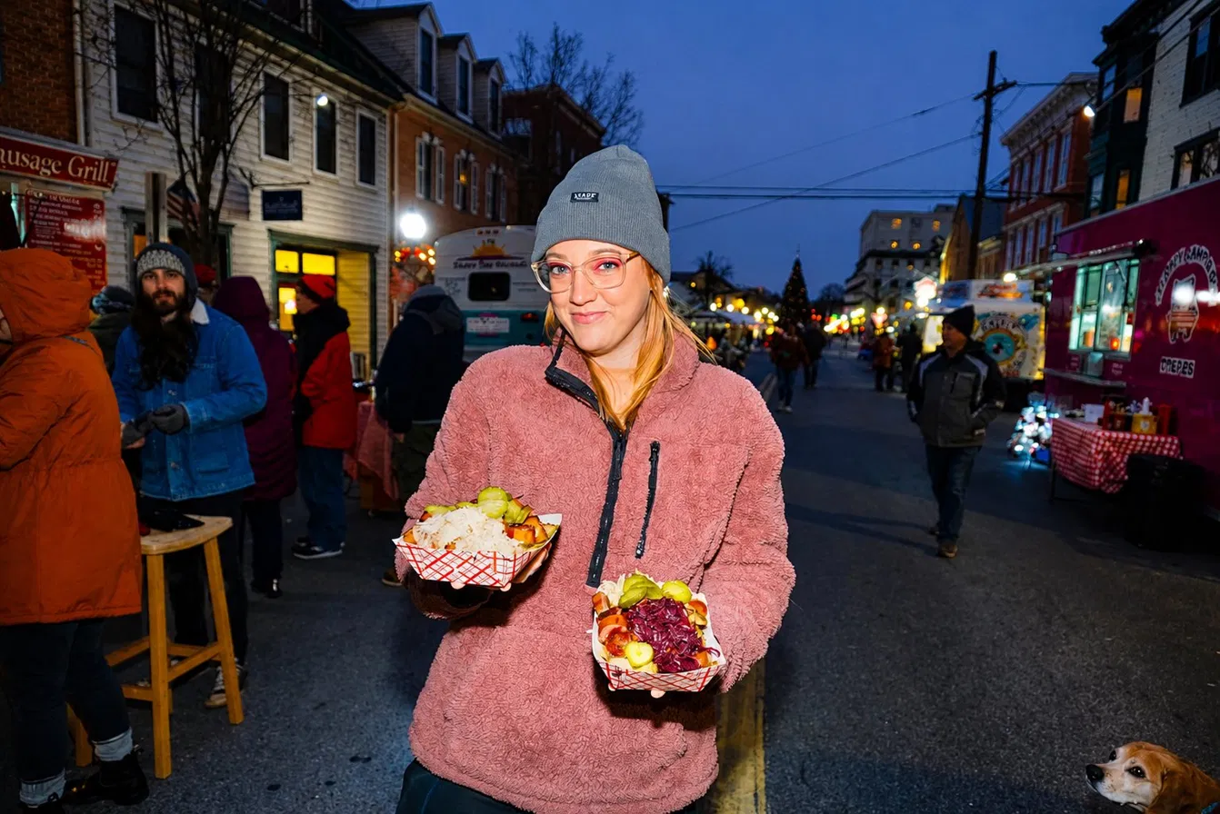 A happy Euro Bites customer carrying two trays of food at a winter street festival